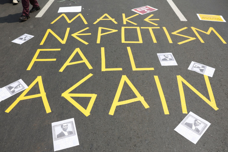 A person walks past a “Make nepotism fall again“ sign during a protest outside the Senayan legislative complex in Jakarta on Aug. 22, 2024 against a revision to the Regional Elections Law, which analysts believe goes through a rushed process of legislation and is designed to block popular candidates running in the upcoming simultaneous regional elections.