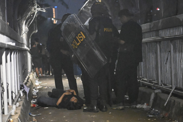 Police surround a protester during a demonstration against the planned revision of the regional election law in front of the House of Representatives complex in Central Jakarta on August 22, 2024.