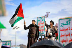 A Yemeni man waves a Palestinian flag as others raise placards during a rally in support of the Palestinians in the Huthi-controlled capital Sanaa on Aug. 23, 2024, amid the ongoing conflict in the Gaza Strip between Israel and the Palestinian Hamas movement.