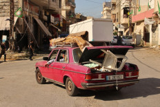 A family, with their belongings strapped to their car, leave their home in the southern Lebanese village of Khiam on August 26, 2024, amid escalations in the ongoing cross-border tensions as fighting continues between Israel and Hamas militants in the Gaza Strip.