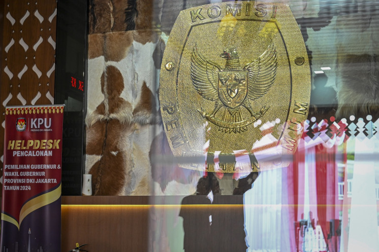 A reflection shows workers setting up the entranceway to the Jakarta General Elections Commission (KPU) office in Jakarta on Aug. 26, 2024, ahead of the candidate registration period for the Jakarta gubernatorial election in November.