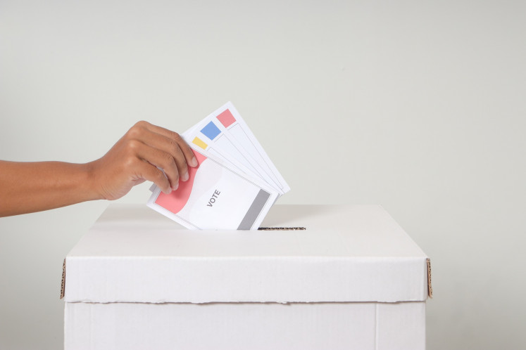 A stock illustration of ballot papers inserted to a ballot box.