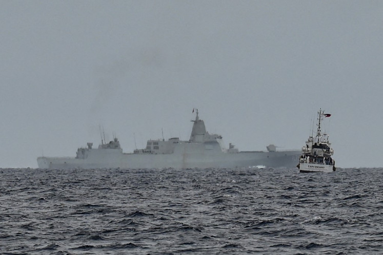 A vessel identified by the Philippine Coast Guard as a Chinese navy ship (background center) is seen past the Philippine Coast Guard ship BRP Cape Engano (right), during a supply mission to Sabina Shoal in disputed waters of the South China Sea on August 26, 2024. Sailors aboard two Philippine Coast Guard vessels crashed through South China Sea waves trying to bring food and other supplies to colleagues holed up inside a remote ring of reefs, as Chinese ships shadowed them. 