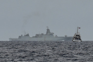 A vessel identified by the Philippine Coast Guard as a Chinese navy ship (background center) is seen past the Philippine Coast Guard ship BRP Cape Engano (right), during a supply mission to Sabina Shoal in disputed waters of the South China Sea on August 26, 2024.