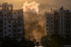 Israeli military vehicles are stationed along a street as a plume of smoke rises during an ongoing raid in the occupied West Bank Jenin refugee camp on September 1, 2024. Since August 30, Israeli soldiers have concentrated operations on Jenin and its refugee camp, a densely-populated community which has long been bastions of Palestinian armed groups.