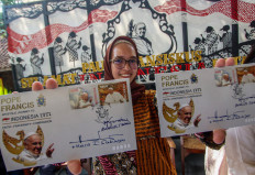 A woman shows samples of a new series of stamps ahead of the visit by Pope Francis during the launch ceremony at the Jakarta Cathedral in Jakarta on Sept. 2, 2024. 
