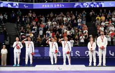 Indonesian gold medalists Ramdani Hikmat and Leani Ratri (center pair), as well as silver medalists Khalimatus Sadiyah and Fredy Setiawan (left pair) gesture, while French bronze medalists Faustine Noel and Lucas Mazur look on as they stand for the Indonesian national anthem, 'Indonesia Raya', during the medal ceremony for the mixed doubles SL3/SU5 badminton category at the Paris 2024 Paralympics on Sept. 2, 2024. 