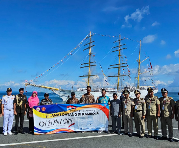 Anggota diaspora Indonesia dan perwira militer Kamboja berdiri dengan spanduk selamat datang pada 16 Agustus 2024 di sebuah pelabuhan di Sihanoukville, Kamboja. Di belakang kelompok tersebut terdapat kapal latih tiga tiang milik Angkatan Laut Indonesia, KRI Bima Suci, yang singgah di pelabuhan tersebut sebagai bagian dari perayaan 79 tahun kemerdekaan Indonesia dan 65 tahun hubungan Indonesia-Kamboja.