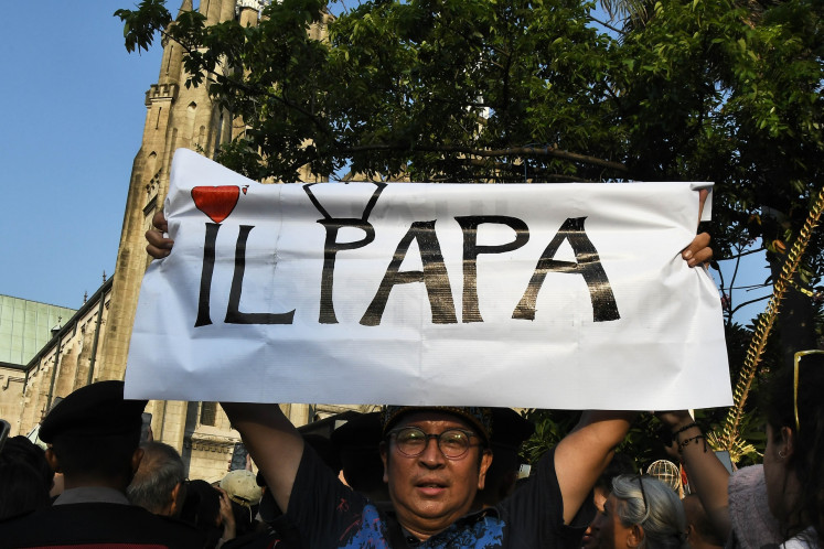 Seorang pria mengangkat spanduk bertuliskan “Il Papa“ pada 4 September 2024, sambil menunggu kedatangan Paus Fransiskus di Katedral Jakarta, Jakarta.