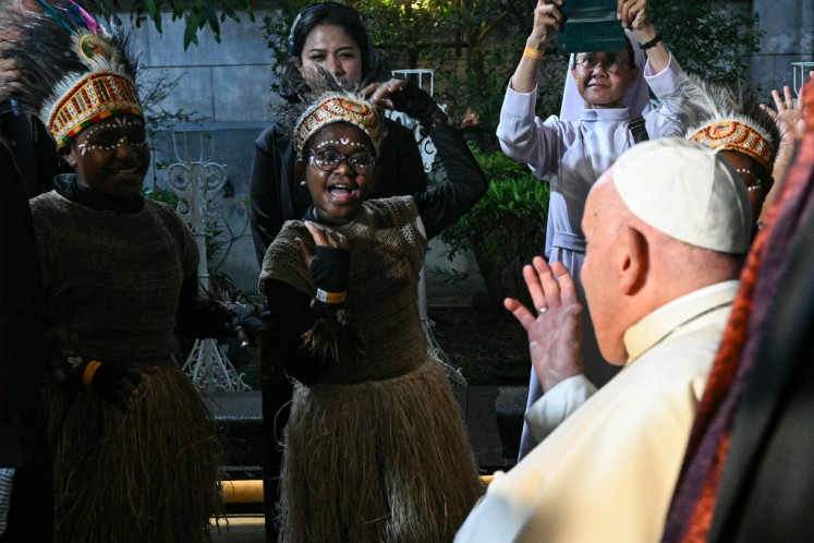 A girl greets Pope Francis (right) on Sept. 4, 2024, as he arrives at the Grha Pemuda youth center in Jakarta.