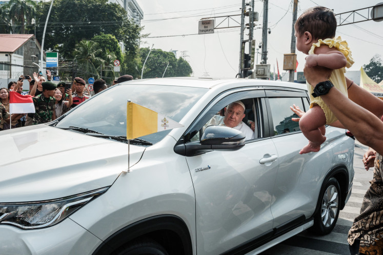 A man holds his baby for Pope Francis to bless as he leaves for Jakarta's Soekarno-Hatta International Airport ahead of his departure to Papua New Guinea's capital Port Moresby on September 6, 2024. Pope Francis left Indonesia for Papua New Guinea on September 6 on the second leg of an arduous 12-day tour of the Asia-Pacific, after delivering a message of religious unity in the world's most populous Muslim-majority nation. 