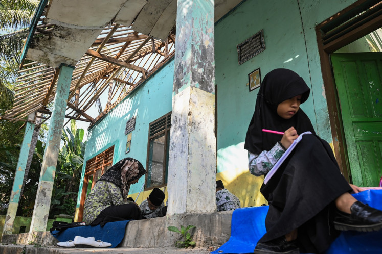 A student studies in the terrace of a heavily-damaged building of MIS Al-Khaeriyah privately Muslim elementary school in Tangerang regency, Banten on Aug. 22, 2024. The school resumes its activities in its yard and residents houses as the school building is heavily damaged and requires a renovation.