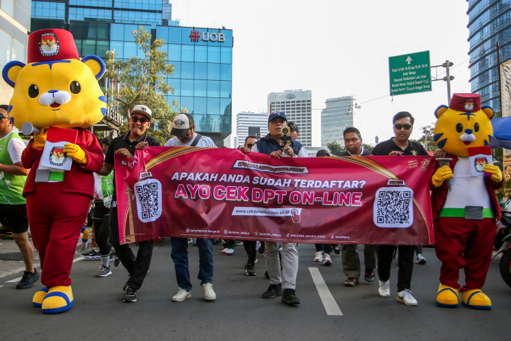 Officials of Central Jakarta General Elections Commission (KPU) hold a banner on voter registration at a car-free day in Jakarta on Sept. 8, 2024 to woo Jakartan voters to cast their votes in the upcoming Jakarta gubernatorial election, slated for Nov. 27.