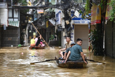 People wade through flood waters on a boat in Hanoi on September 12, 2024, as heavy rains in the aftermath of Typhoon Yagi brought flooding to northern Vietnam. The number of people killed after Typhoon Yagi swept through northern Vietnam bringing flash floods and landslides has risen to 197, the government said on September 12.