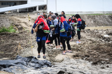 Volleyball players walk along a muddy road near a sporting venue in Deli Serdang, North Sumatra, on Sept. 10, 2024. A volleyball match scheduled for that day was postponed to Wednesday due to several problems, including the poor access. 