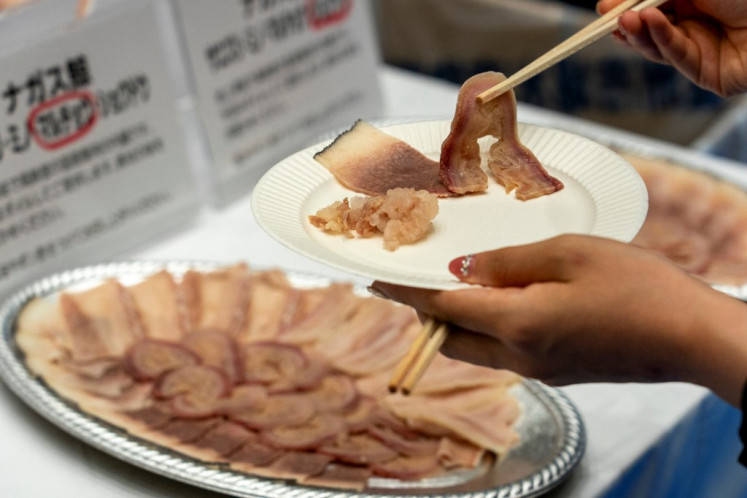 Seorang tamu menggunakan sumpit untuk mengambil dan mencicipi daging mentah dari paus sirip di pameran dan pertemuan bisnis paus sirip produksi dalam negeri yang diselenggarakan oleh perusahaan perburuan paus Jepang Kyodo Senpaku di pasar Toyosu, Tokyo pada tanggal 13 September 2024. Potongan daging paus sirip seukuran gigitan tersedia untuk diendus dan dicicipi pada tanggal 13 September saat industri perburuan paus Jepang berupaya untuk menghidupkan kembali selera terhadap sumber protein yang sebagian besar telah kehilangan peminatnya.