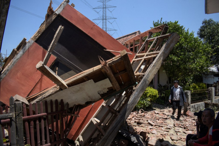 A man walks next to a collapsed house in Kertasari, West Java, after a 5-magnitude earthquake struck on Sept. 18, 2024. At least two people died and hundreds were injured in the quake.