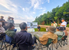 Hartono, the head of the Peatland and Mangrove Restoration Agency (BRGM), engages in an on-site discussion with advisors from the Ministry of Environment and Forestry and the Ministry of Maritime Affairs and Fisheries, as well as experts from Borneo Tarakan University, at a community-owned shrimp farm. (Courtesy of BRGM)