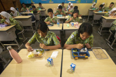 Students of SMP 1 Salatiga state junior high school eat boxed lunch packages during a free meal program trial in Salatiga, Central Java, on Sept. 12.