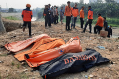 Bekasi Disaster Mitigation Agency (BPBD) and police personnel stand on Sept. 22, 2024, near the body bags of seven male teenagers drowned in the Bekasi River in Bekasi, West Java.