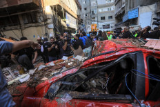 Bystanders and reporters check the destruction in a street under a residential building whose top two floors were hit by an Israeli strike in the Ghobeiri area of Beirut's southern suburbs on September 24, 2024. A Lebanese security source said on September 24 that an Israeli strike hit Hezbollah's south Beirut stronghold, as the Israel army confirmed it carried out the strike in the Lebanese capital without giving further details.