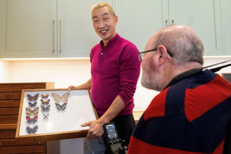 John McArthur (right), a collector of butterflies from around the world, and his husband and carer James Hu pose with a butterfly collection during an interview with AFP at their house in Karori, a suburb of Wellington on Sept. 17. 2024. From his electric wheelchair, New Zealander John McArthur admits it was a wrench watching his life's work, a collection of 20,000 butterflies, being packed and shipped halfway around the world.