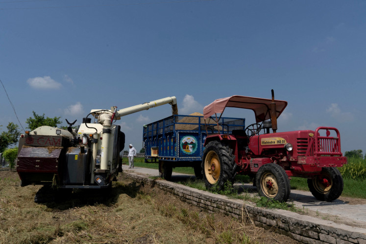 A paddy harvester is used to deposit rice crops in a tractor trolley in a field in Kalampura village in the northern state of Haryana, India, on Sept. 9, 2024.