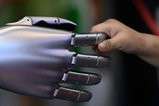 A child grabs the finger of a Tesla humanoid robot on display during the World Intelligence Expo in Tianjin, China on June 23, 2024.
