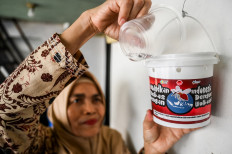 A resident pours water on Oct. 4, 2024, into a bucket filled with Aedes aegypti mosquito larvae infected with the Wolbachia bacteria in Kembangan district, West Jakarta. The Jakarta administration is releasing the Wolbachia-infected mosquito eggs in an effort to control the spread of dengue in the city.