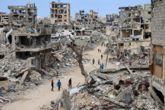 Palestinians walk on a dirt road lined with building rubble in the Shujaiya neighborhood of Gaza City on October 7, 2024, on the first anniversary of the ongoing war in the Gaza Strip between Israel and the Palestinian Hamas group.