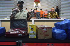 An investigator (left) shows confiscated money at a press briefing on Oct. 8, 2024 at the Jakarta headquarters of the Corruption Eradication Commission (KPK), attended by KPK deputy chair Nurul Ghufron (center) and spokesperson Tessa Mahardika (right). The cash and other items were seized during a raid in South Kalimantan that also resulted in the arrest of six suspects, including South Kalimantan Public Works and Housing Agency head Yulianti Erlynah, as well as the naming of South Kalimantan Governor Sahbirin Noor as a suspect in the case.
