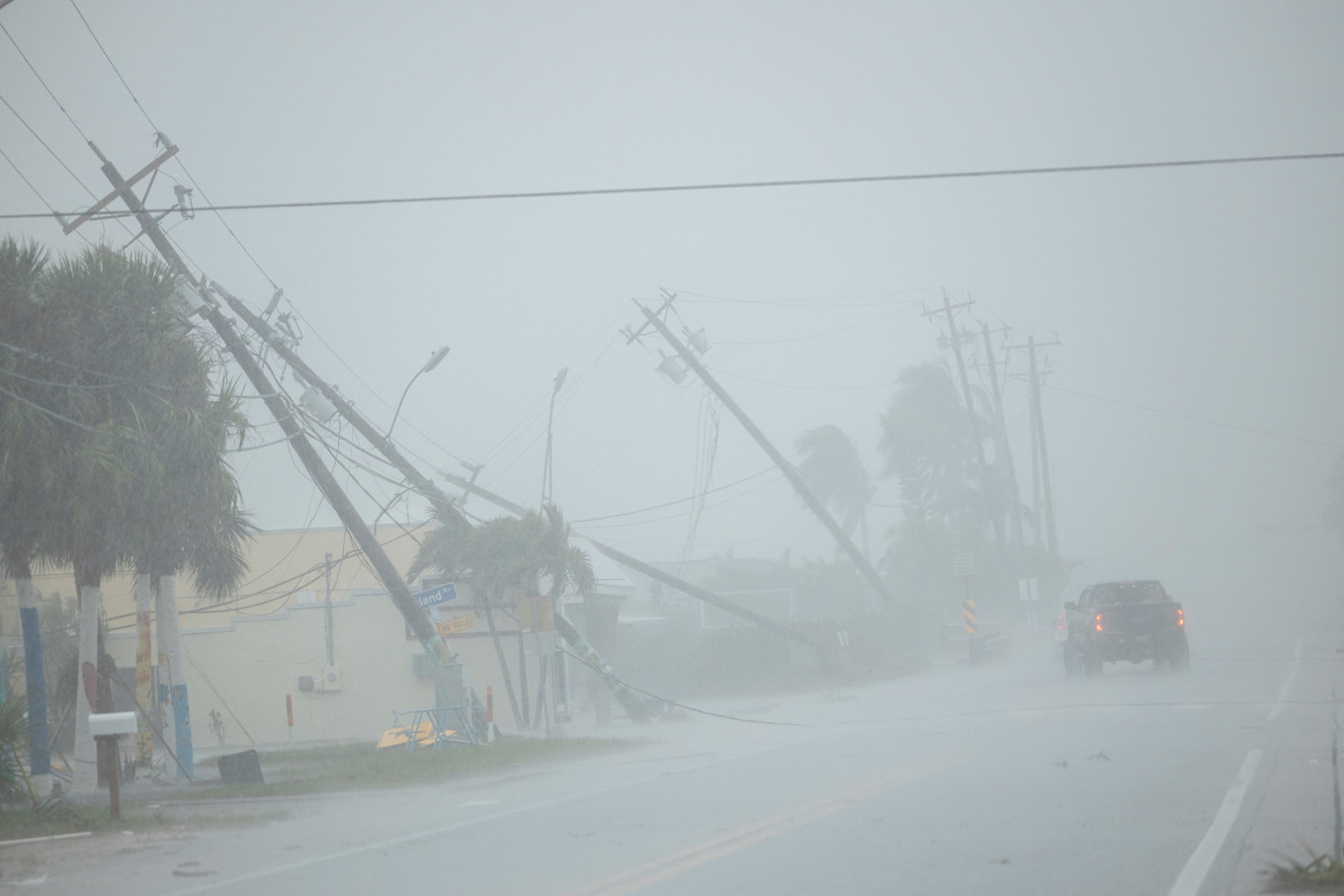 A motorist drives past broken utility poles downed by strong wind gusts as Hurricane Milton approaches Fort Myers, Florida, the United States, on Oct. 9, 2024.