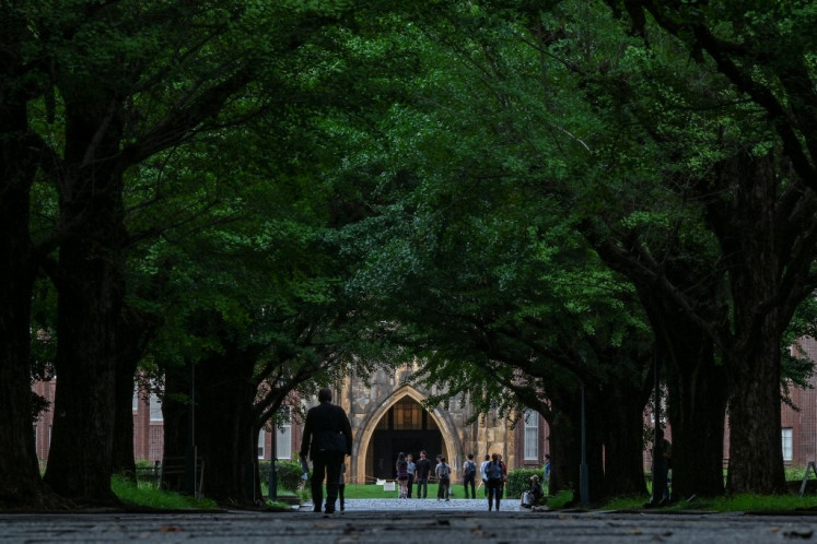 People walk along a road lined with ginkgo trees at the University of Tokyo, also known as Todai, in Tokyo, on Aug. 22, 2024. 