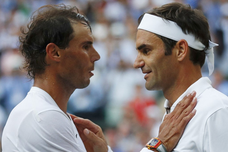 Switzerland's Roger Federer (right) shakes hands and embraces Spain's Rafael Nadal (left) after Federer won their men's singles semi-final match on day 11 of the 2019 Wimbledon Championships at The All England Lawn Tennis Club in Wimbledon, southwest London, on July 12, 2019. Rafael Nadal announced on Oct. 10, 2024 he will retire from professional tennis after the Davis Cup finals in November, ending a career in which he won 22 Grand Slam titles and Olympic singles gold.