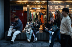 People rest outside a clothing store in a shopping mall during a week-long holiday marking China's National Day, in Beijing on Oct. 4, 2024.