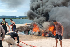 Police officers and residents battle a boat fire on Oct. 12, 2024 at Bobong Port in Taliabu Island regency, North Maluku. The speedboat was carrying at least 32 people, including North Maluku gubernatorial candidate Benny Laos, campaign officials and crew, when it exploded while refueling, according to a police statement.
