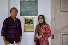 In this picture taken on September 25, 2024, historian Eddy Supangkat (left) and Sri Sarwanti, head of Salatiga's library and archives office, pose near a plaque bearing the name of French poet Arthur Rimbaud at the mayor's residence in Salatiga, Central Java. In the summer of 1876, rebel French poet Arthur Rimbaud arrived in Java, enlisting in the colonial Dutch army before deserting after just two weeks, an escape still shrouded in mystery nearly 150 years later. 
