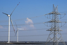 An electricity transmission tower and wind turbines are pictured at the Adani Green Renewable Energy Plant in Khavda, in India's Gujarat state, on Oct. 15, 2024.