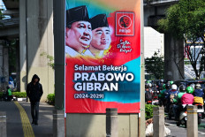 A pedestrian (left) walks near a banner congratulating president-elect Prabowo Subianto and vice president-elect Gibran Rakabuming Raka ahead of their Oct. 20 inauguration in Jakarta on Oct. 17. 
