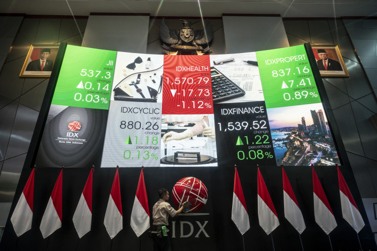 Workers clean the Indonesia Stock Exchange (IDX) logo under a screen showing movements of the Jakarta Composite Stock Price Index (JCI) on Oct. 18, 2024, at the IDX in Jakarta. The IDX Composite recovered by 0.09 percent to close at 6,983.86 on Dec. 20, 2024.