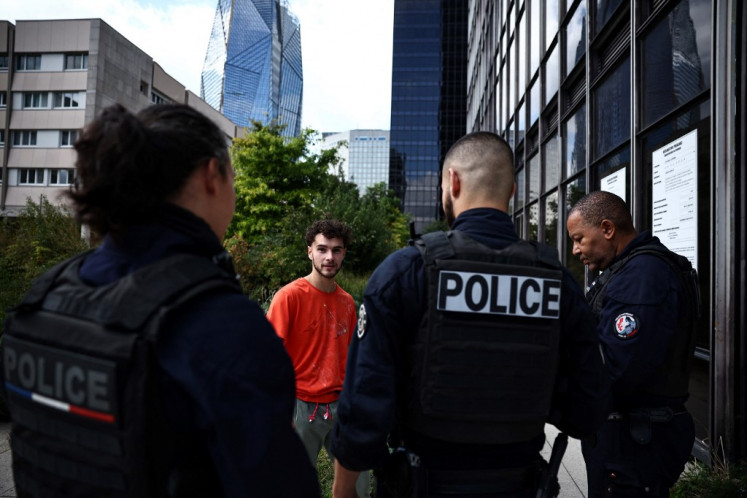 L'alpiniste urbain français Titouan Leduc répond aux policiers après avoir escaladé la Tour Franklin, un gratte-ciel de bureaux de 115 mètres de haut situé dans le quartier d'affaires de La Défense, à l'ouest de Paris, le 3 octobre 2024. Leduc, un urbain de 23 ans grimpeur du nord-est de la France, aime escalader les gratte-ciel sans cordes ni équipement spécialisé, portant seulement une paire de chaussures d'escalade.