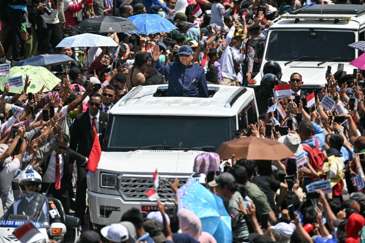 Newly inaugurated President Prabowo Subianto (center) waves to his supporters as he heads to the State Palace after the inauguration ceremony at the Senayan legislative complex in Jakarta on Oct. 20, 2024.