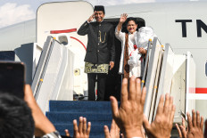 Former president Joko “Jokowi“ Widodo (left) and former first lady Iriana Widodo gesture to a waving crowd on Oct. 20, 2024, as they prepare to board the Indonesian Air Force’s VVIP plane at Halim Perdanakusuma Air Force Base in East Jakarta to return to their hometown of Surakarta, Central Java.