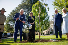 Britain's King Charles III plants a tree as Australia's Governor-General Sam Mostyn (center) and Queen Camilla (right) watch at Government House in Yarralumla, Canberra, Australia, on October 21, 2024. 