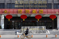 A woman cycles past the Beijing Stock Exchange building adorned with Lunar New Year decorations, on the Financial Street in Beijing, China, on Feb. 8, 2024.