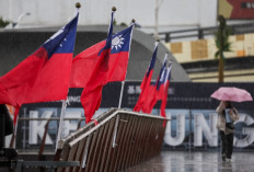 A woman walks past a Taiwanese national flag at Maritime Plaza in Keelung on October 22, 2024. China's military began a live fire exercise near Taiwan, maintaining pressure on the self-ruled island after staging large-scale drills and President Xi Jinping called for troops to prepare for war. 