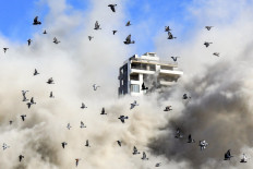 A flock of pigeons flies away as a smoke cloud erupts after a rocket fired by an Israeli war plane hit a building in Beirut's southern suburb of Shayah on Oct. 22, 2024, amid the ongoing war between Israel and Hezbollah.