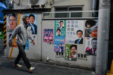 This photo taken on Oct. 20, 2024 shows a man walking past a wall displaying various posters, many with candidates in the upcoming Oct. 27 general election, along a street in the Shinjuku district of central Tokyo.