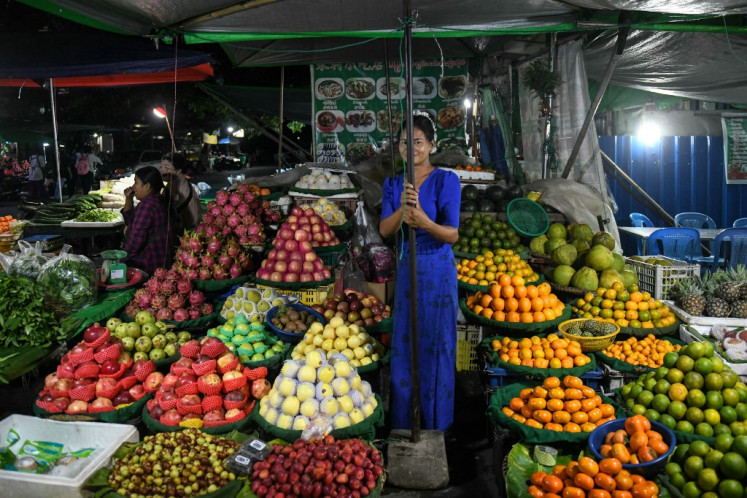 Seorang penjual buah menunggu pelanggan di pasar malam di Mandalay pada 23 Oktober 2024. Di pinggiran Mandalay, tentara Myanmar yang gugup menjaga pos pemeriksaan hanya beberapa kilometer dari pemberontak yang mengincar bekas ibu kota kerajaan berpenduduk 1,5 juta orang itu.