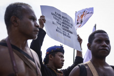A member of an indigenous community holds a poster that reads “We need regulations that protect our rights from state and corporate crimes“ on Oct. 11, 2024, during a protest in front of the Senayan Legislative Complex in Jakarta. The protesters demanded that lawmakers push for protection of indigenous communities' rights as well as the resolution of agrarian conflicts.
